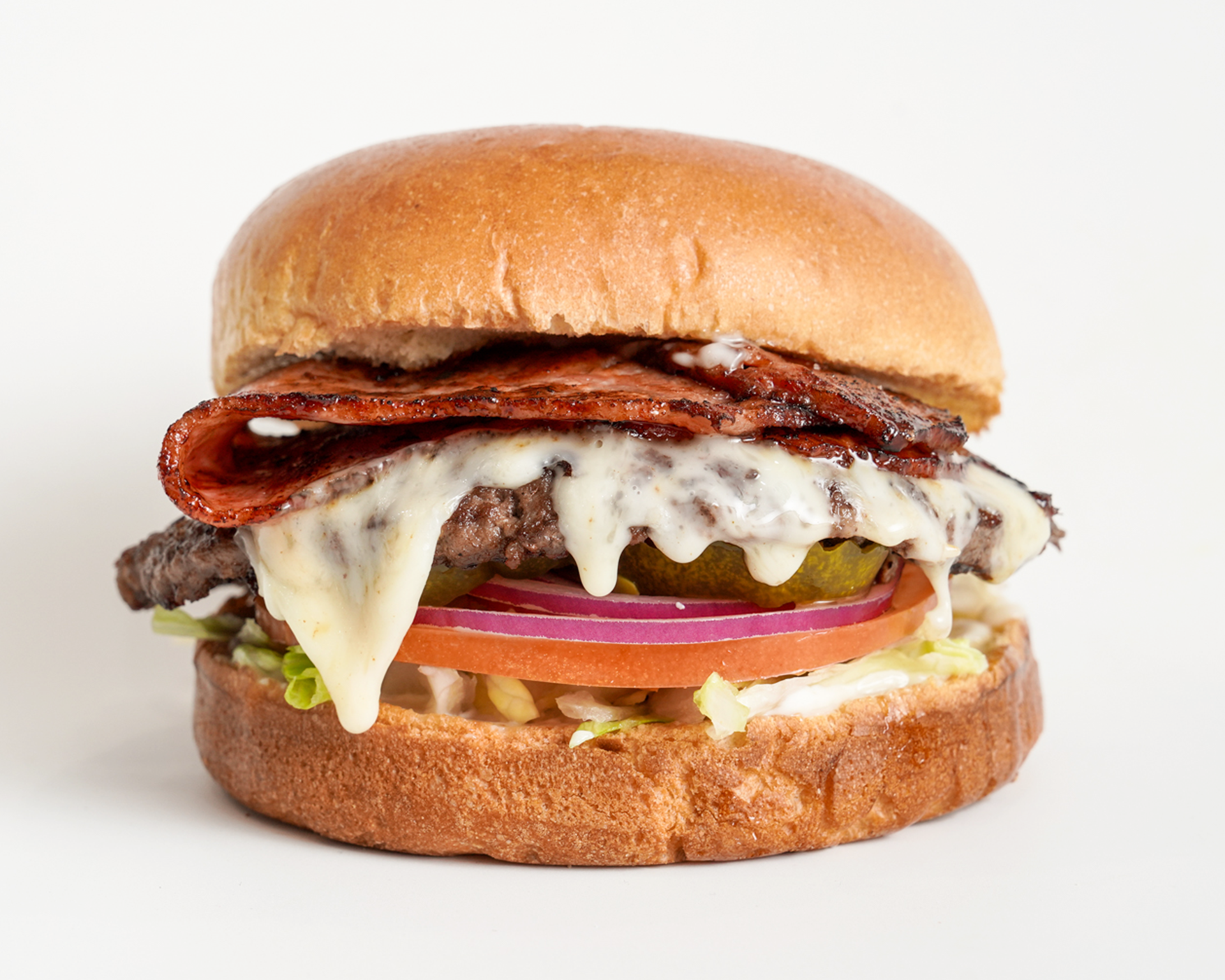Burger with bacon, cheese, tomato, onion, and pickles on a toasted bun.