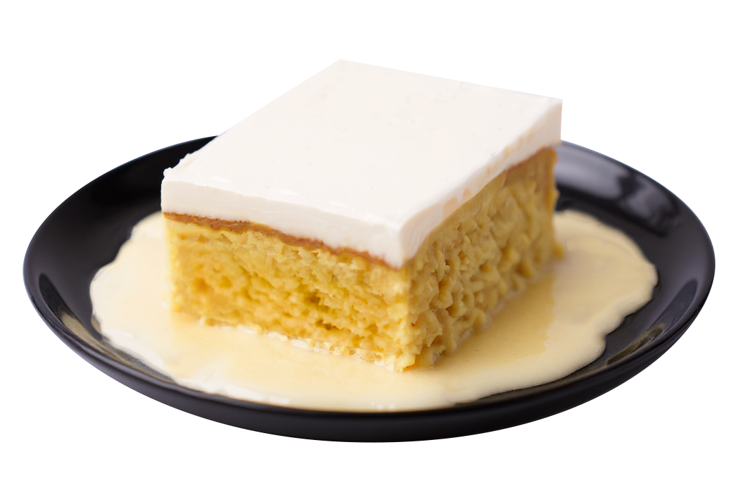 Tres leches cake slice with white frosting, served on a black plate with creamy sauce.
