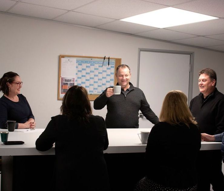 A group of people are sitting around a table drinking coffee