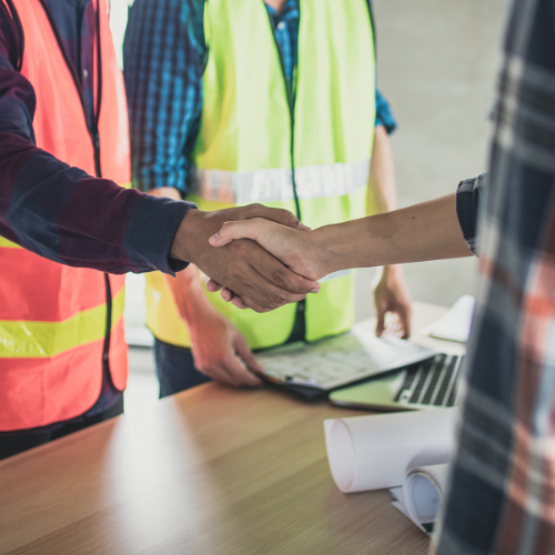 A group of construction workers are shaking hands over a table.
