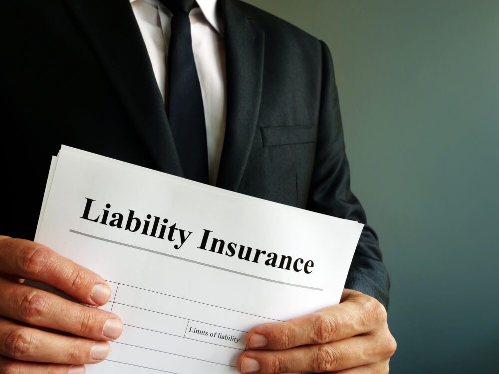 A Man in a Suit and Tie is Holding a Liability Insurance Form — Morris Legal & Conveyancing in Forster, NSW
