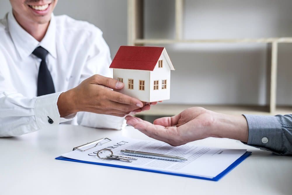 Real Estate Agent Hands Miniature House