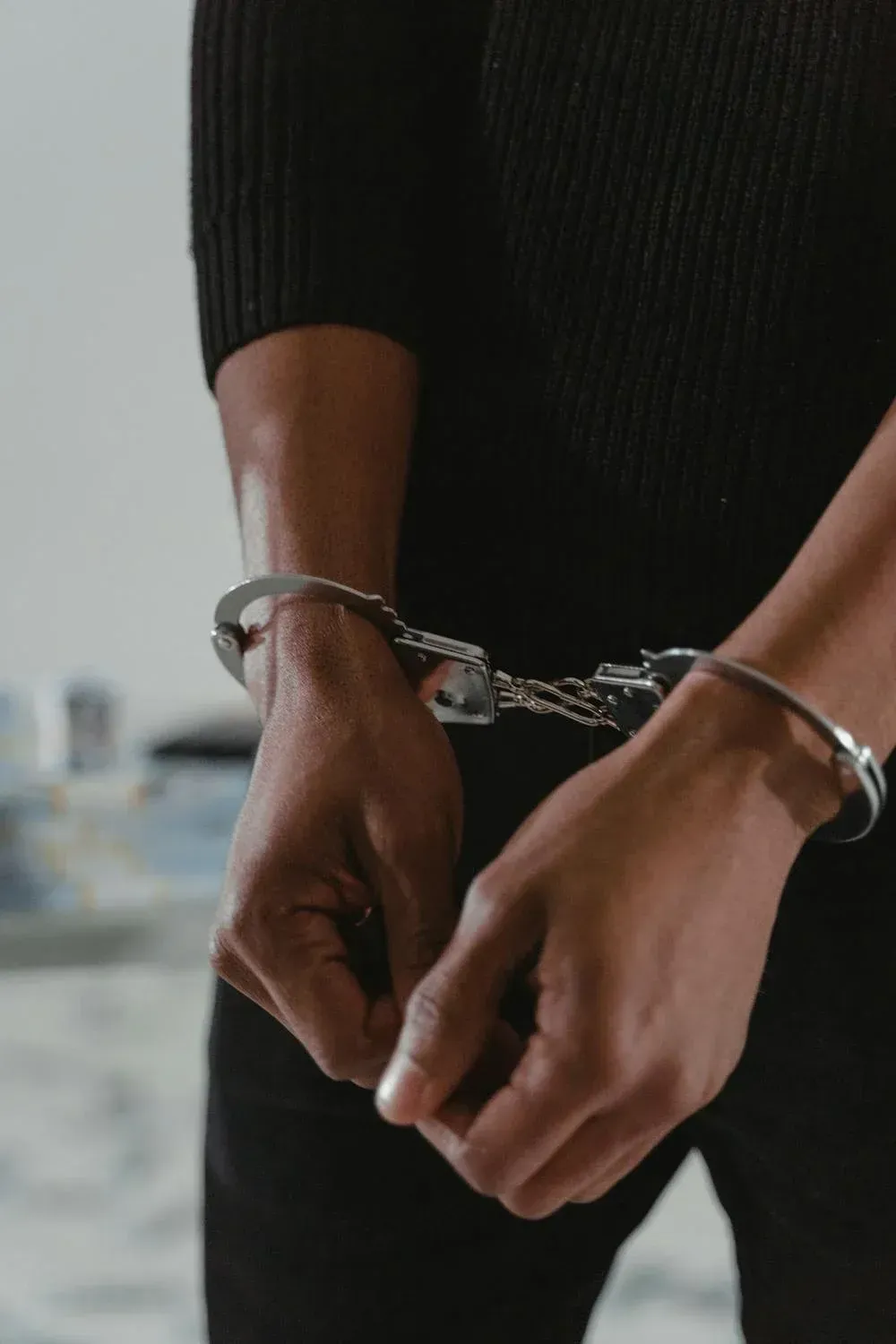 A man wearing handcuffs is standing in a room.