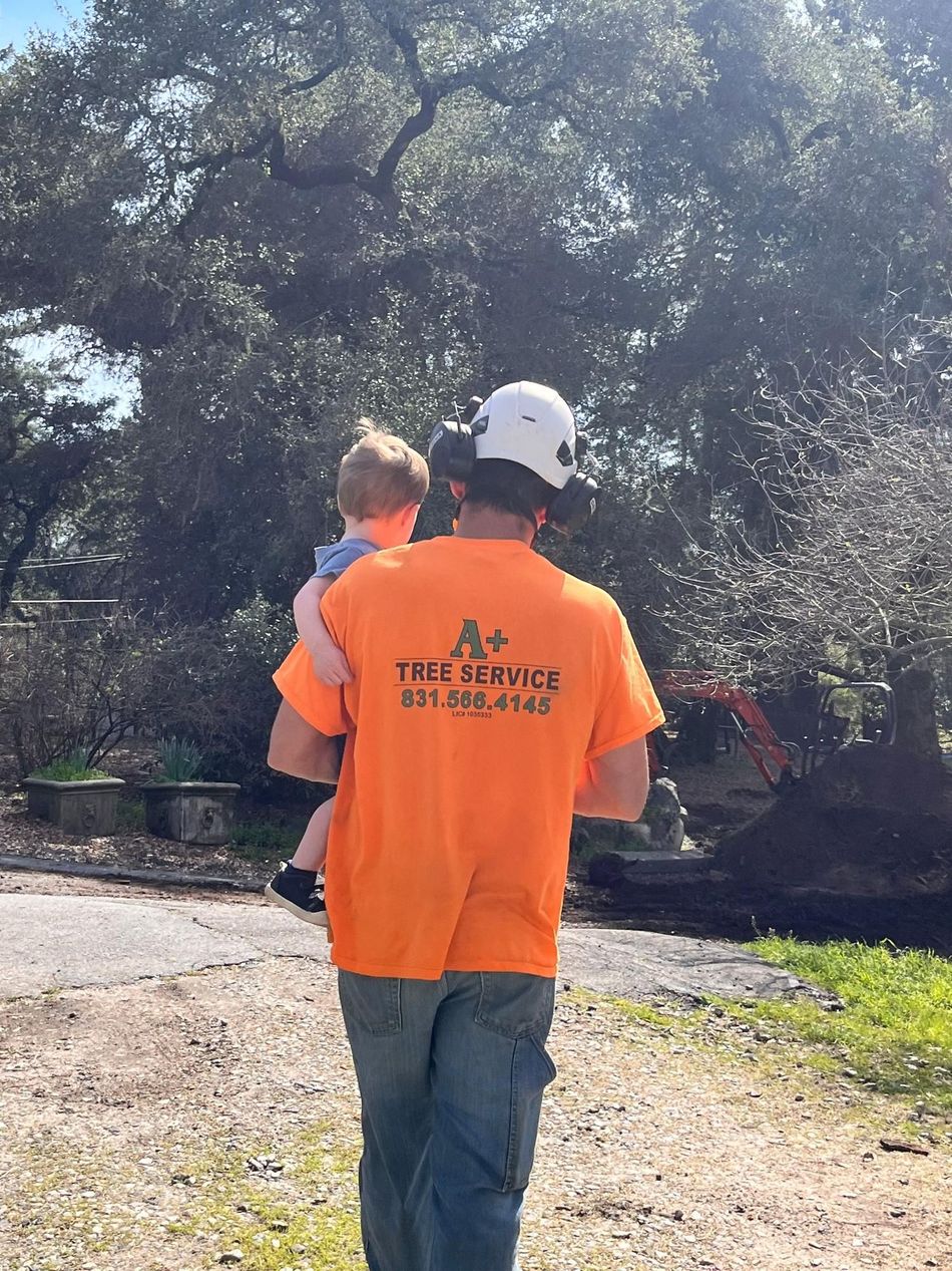 A man in an orange shirt is holding a baby in his arms.
