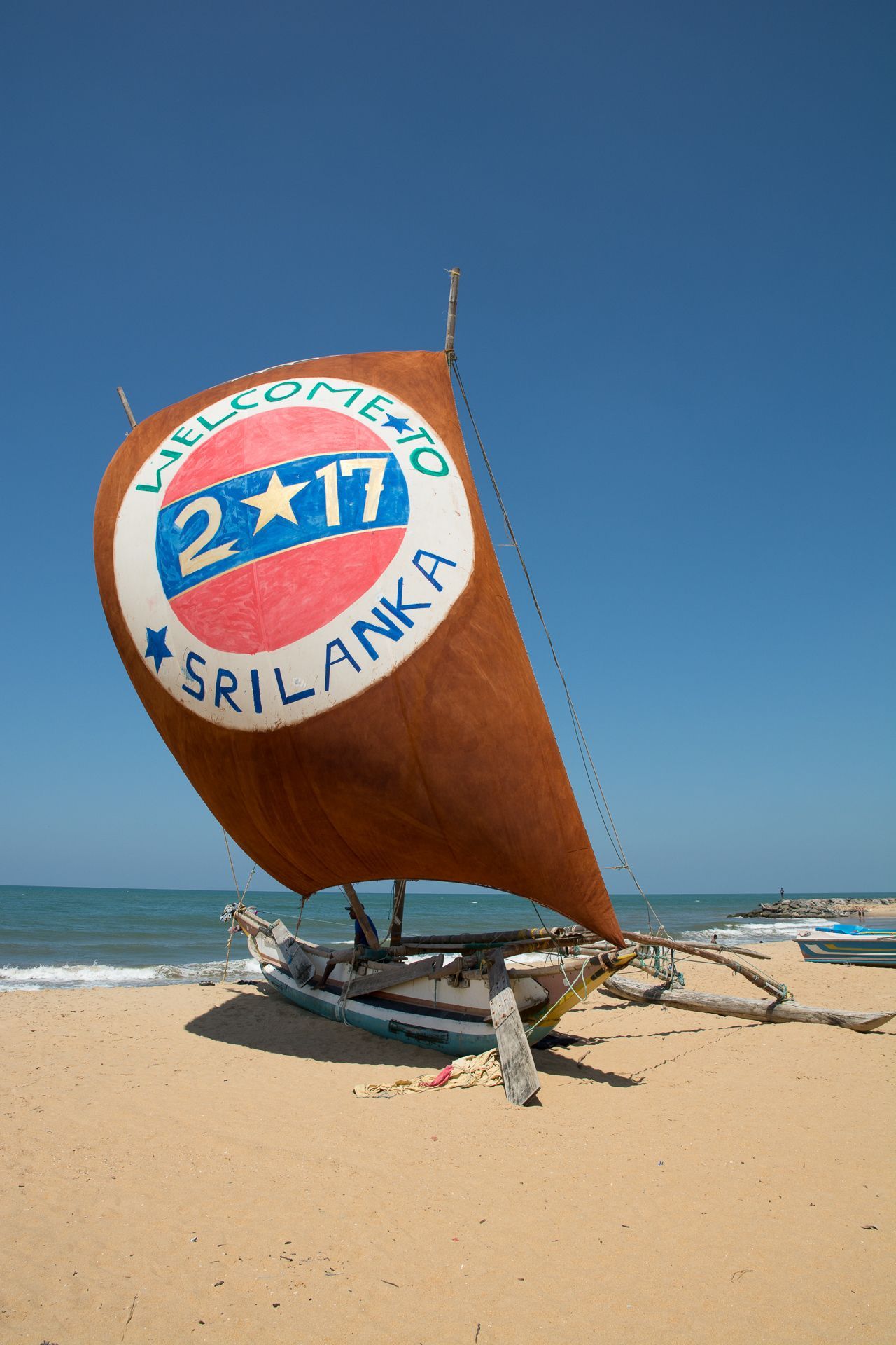 Een boot op een zandstrand met een zeil waarop 