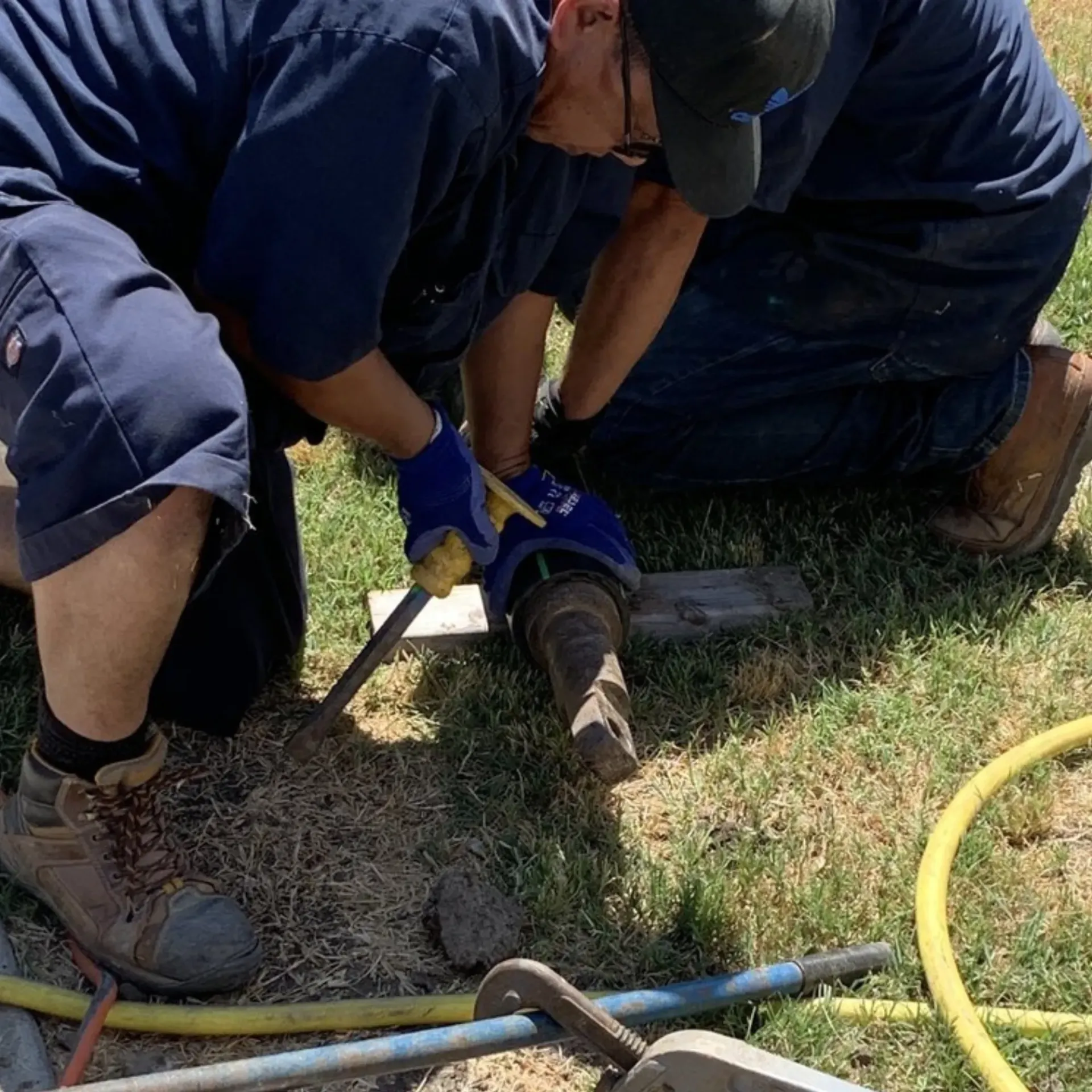Ted & Bros Plumbing | man is kneeling down in the grass working on a pipe
