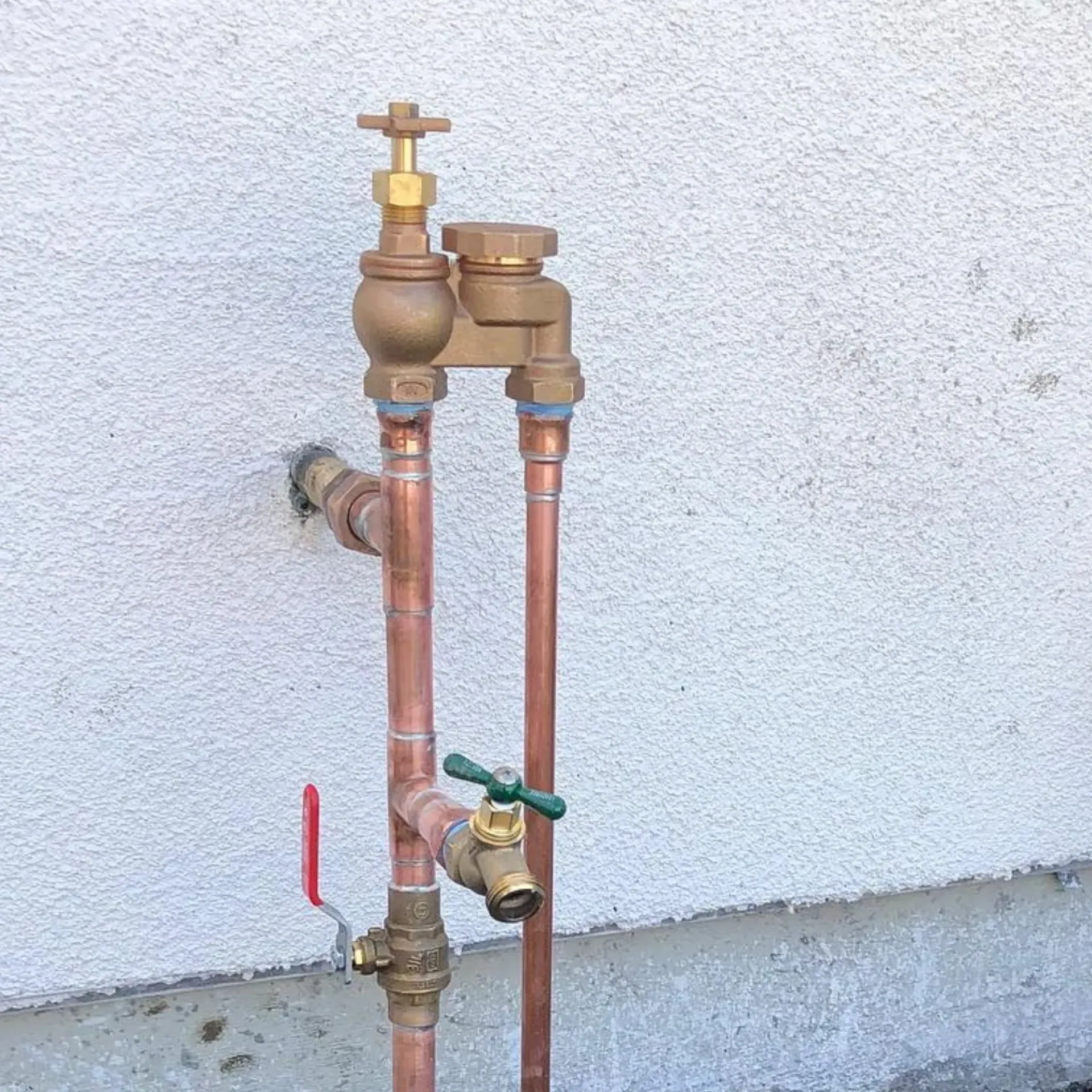 Ted & Bros Plumbing | copper pipe with a green handle is attached to a wall.