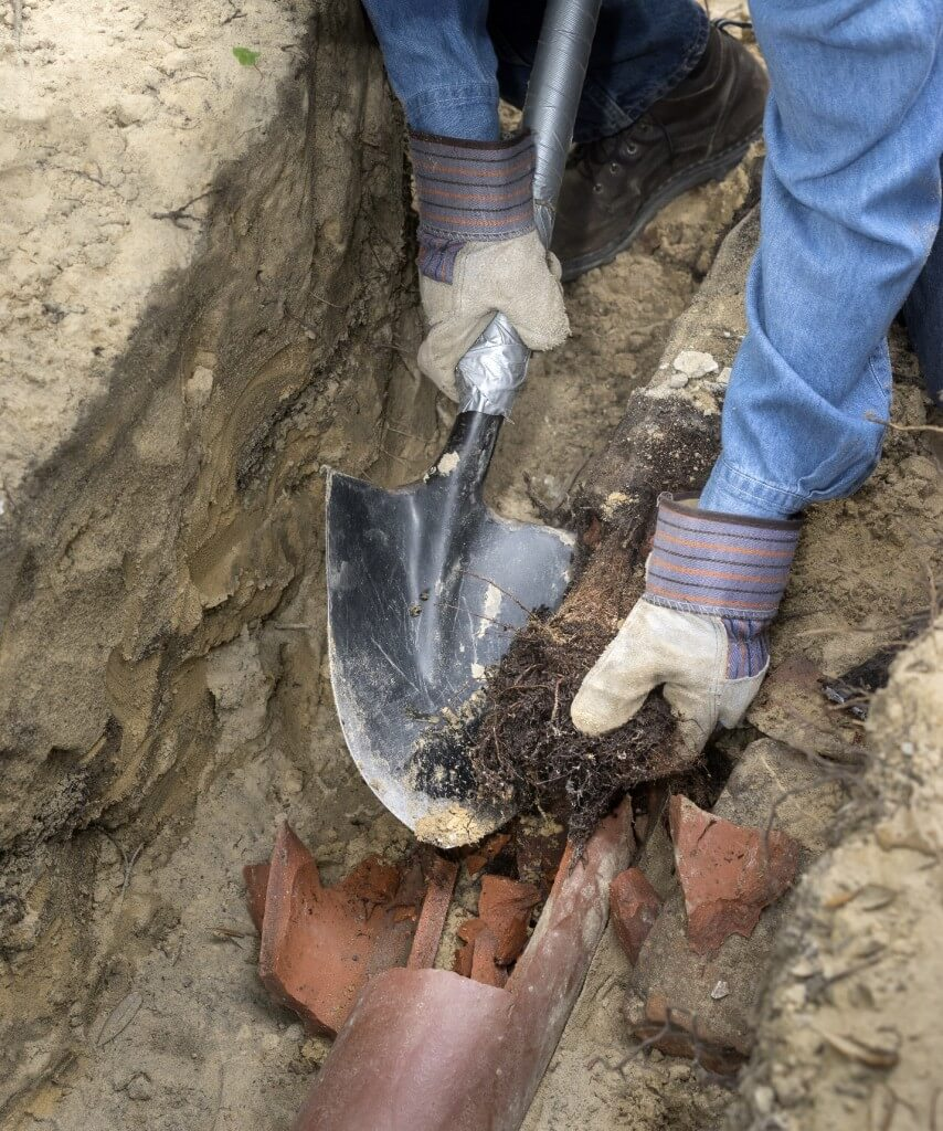 Ted & Bros Plumbing | Two men are working on a drainage system in a yard.