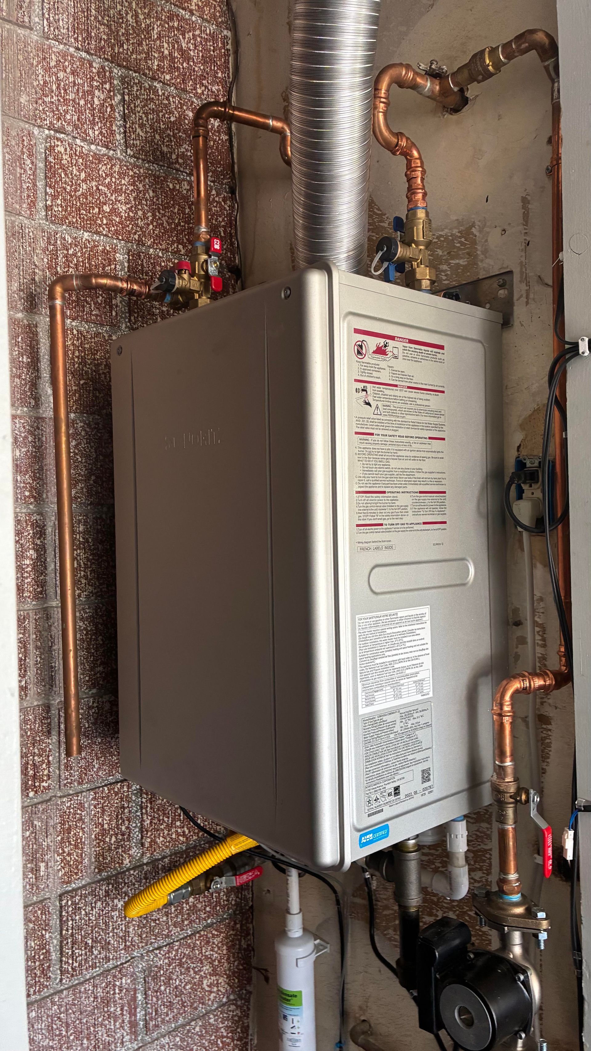 Ted & Bros Plumbing | man in a red shirt is working on a water heater