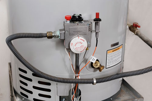 Ted & Bros Plumbing | man in a red shirt is working on a water heater