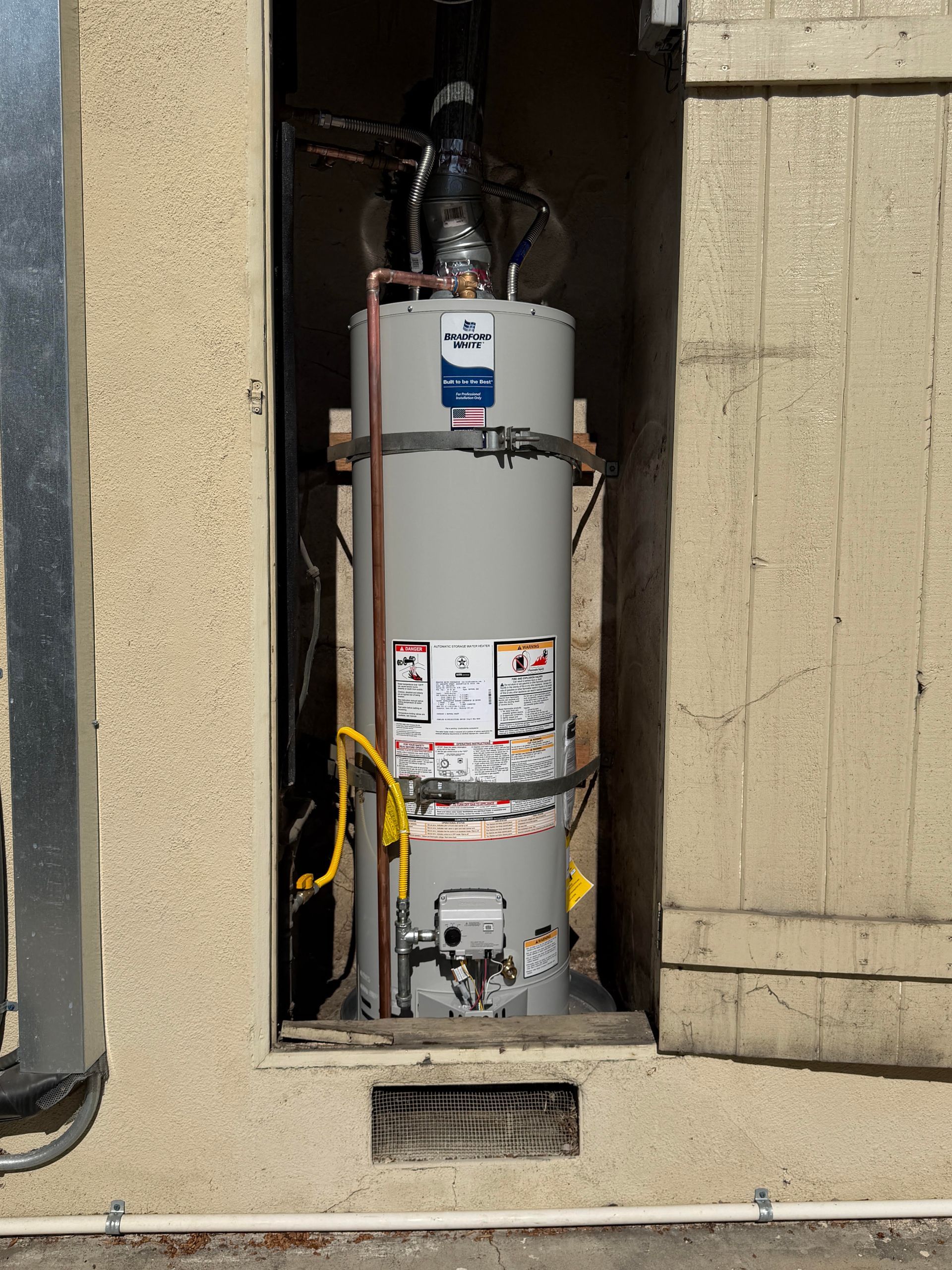 Ted & Bros Plumbing | man in a blue shirt is working on a water heater
