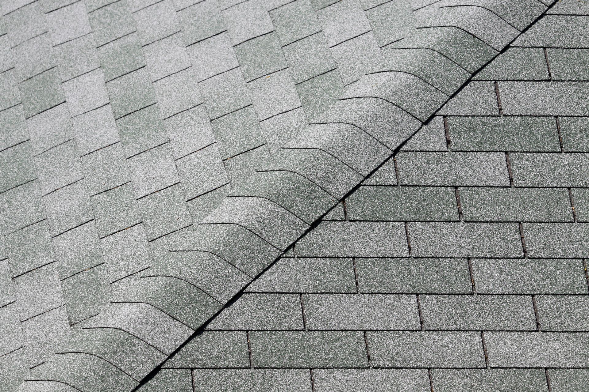 Gray shingle roof with a diagonal seam between two sections, showing different patterns and shades