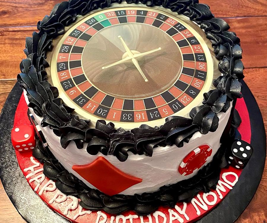 Casino-themed cake with roulette wheel top, black trim, and “Happy Birthday Momo” lettering