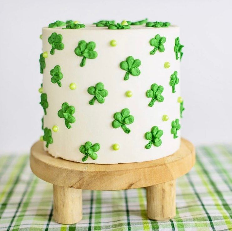White cake with green shamrock decorations on a small wooden stand