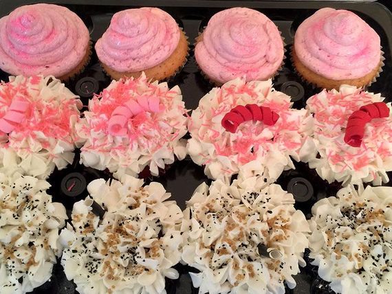 Row of pink, white, and cream frosted cupcakes with piped swirls and flower-like decorations