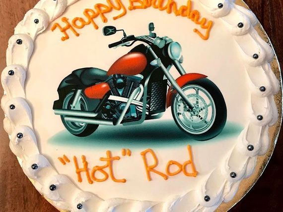 Motorcycle-themed birthday cake with orange “Happy Birthday” and “Hot Rod” icing