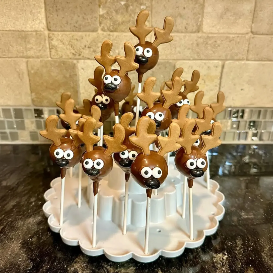 Chocolate reindeer cake pops with candy eyes on white platter, festive dessert display