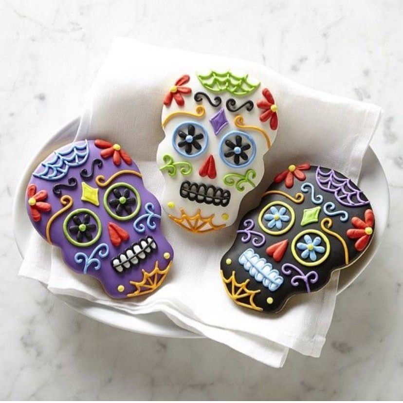 Three colorful decorated skull cookies on a white napkin