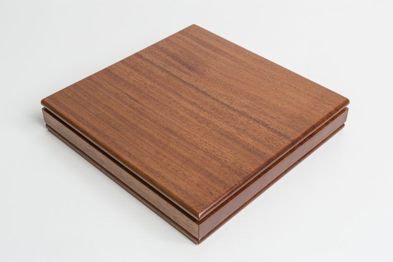 A square piece of wood is sitting on a white surface