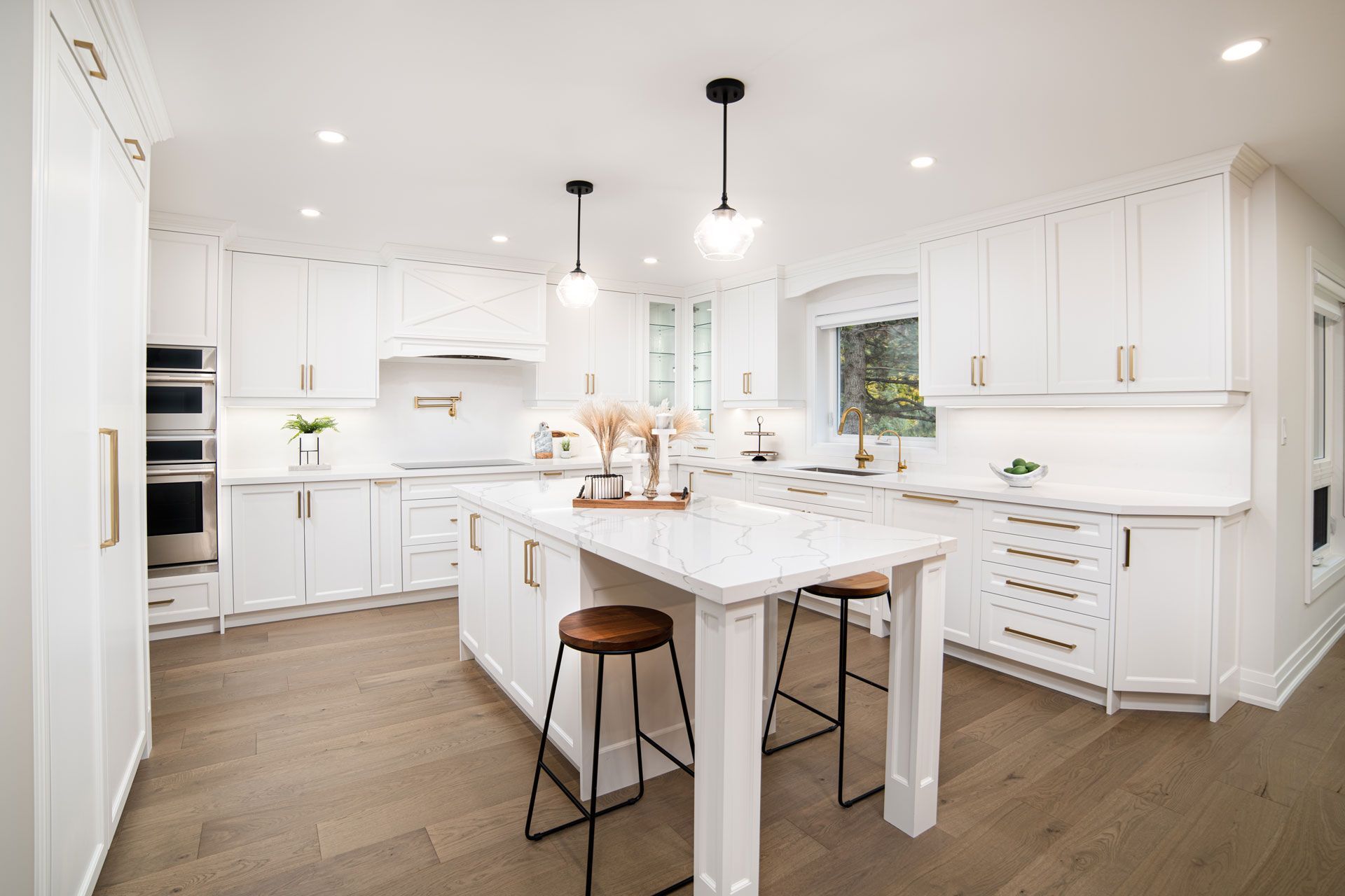 Bright white modern kitchen with island, pendant lights, wood floor, and built-in cabinets