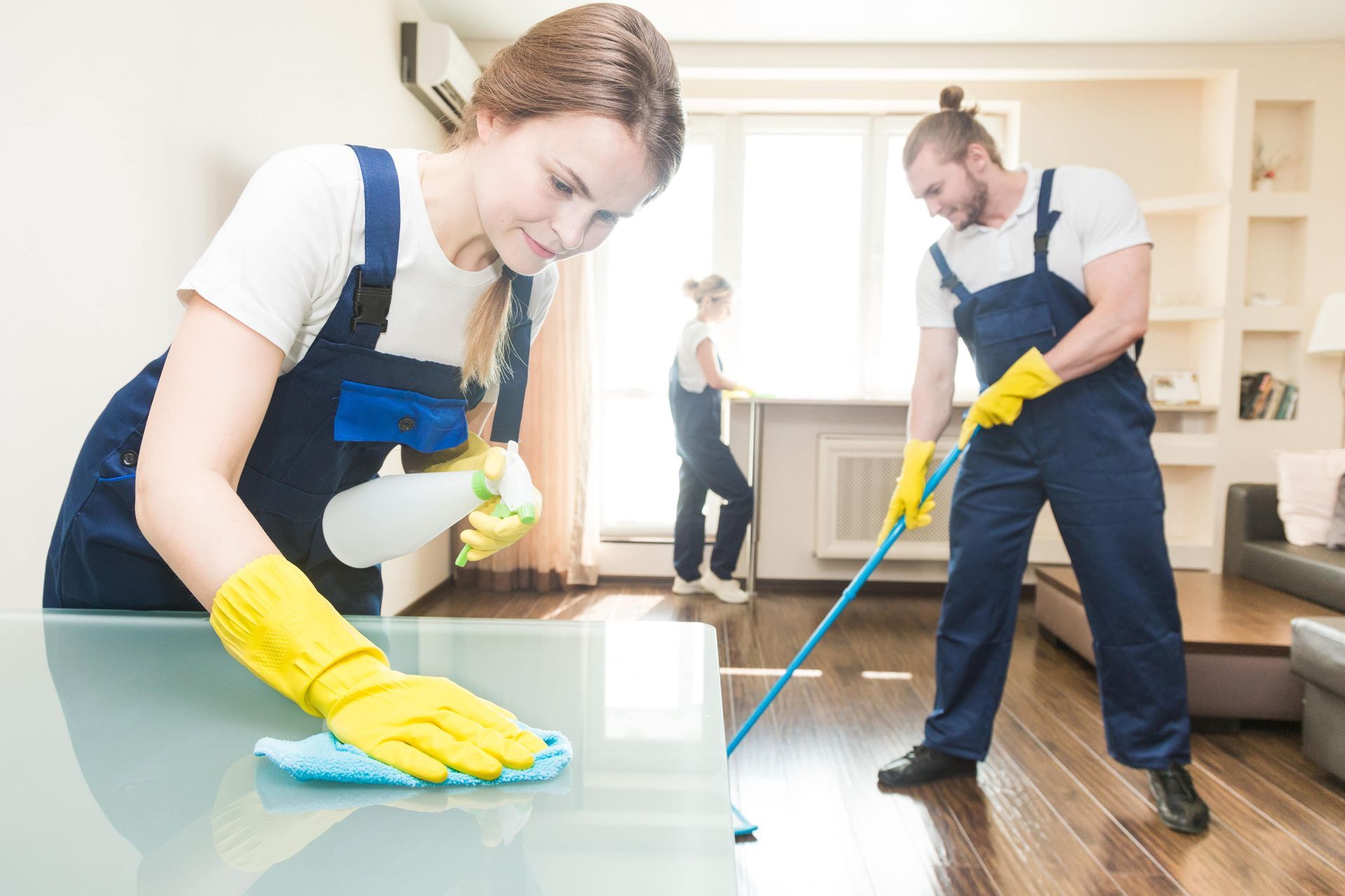 A man and a woman are cleaning a living room.