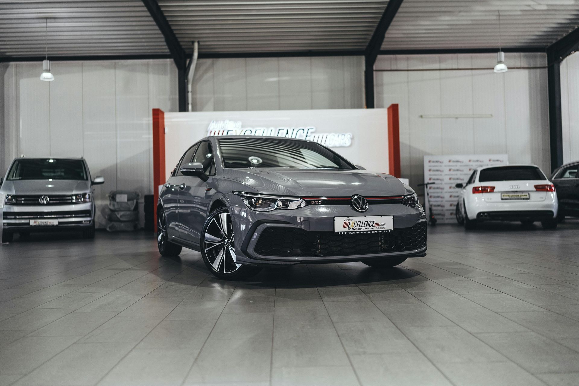 A volkswagen golf r is parked in a showroom next to other cars.