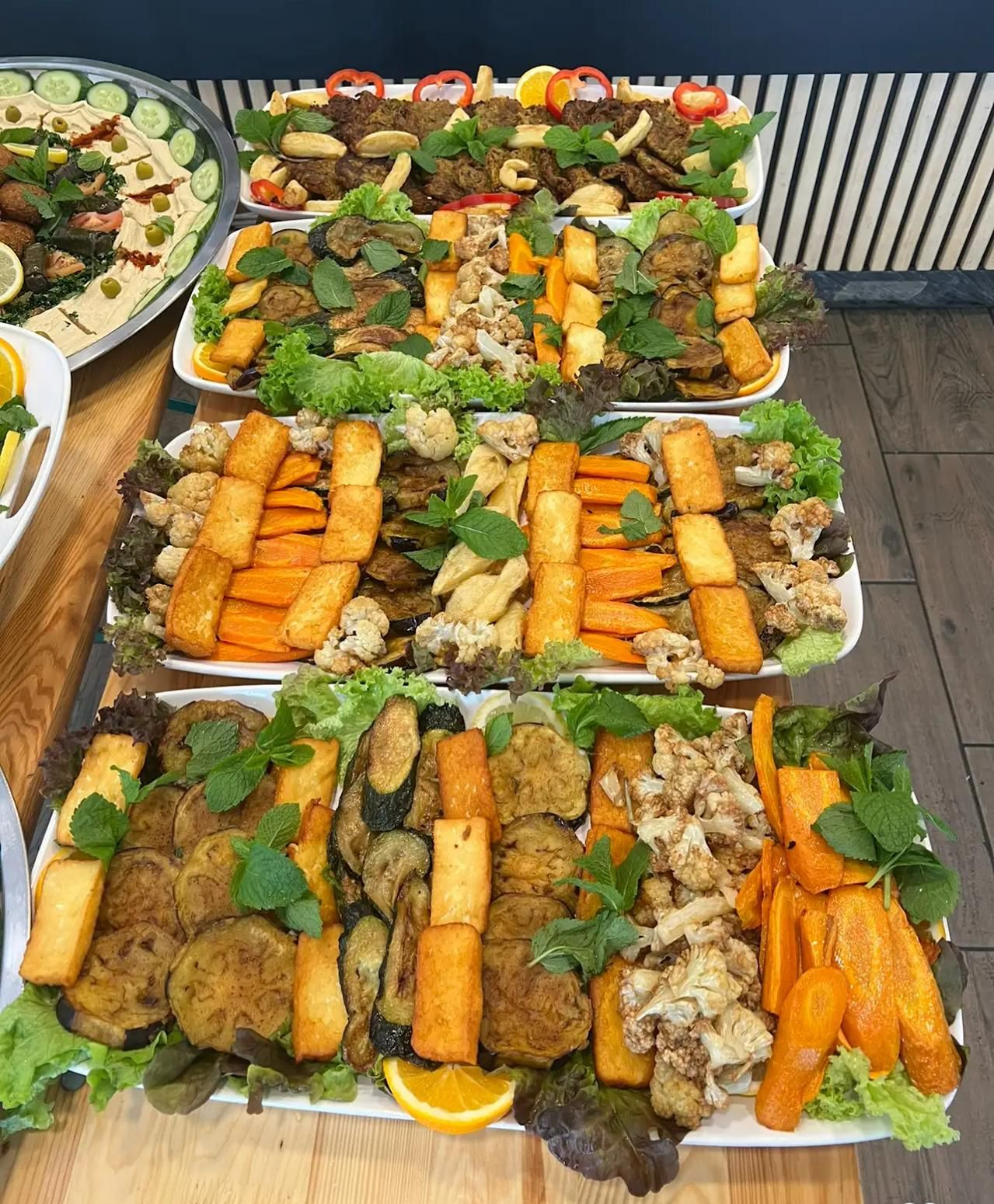 Buffet platters with various cooked vegetables and herbs.