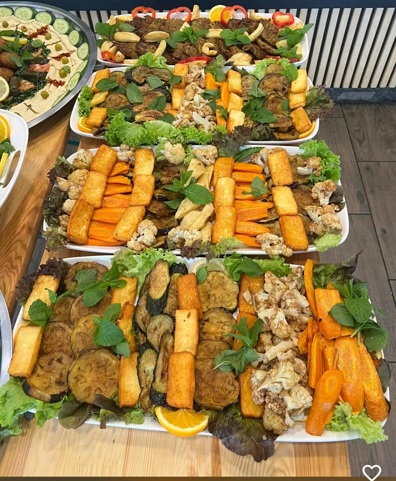 Platters of cooked vegetables: carrots, eggplant, cauliflower, and more, garnished with herbs.