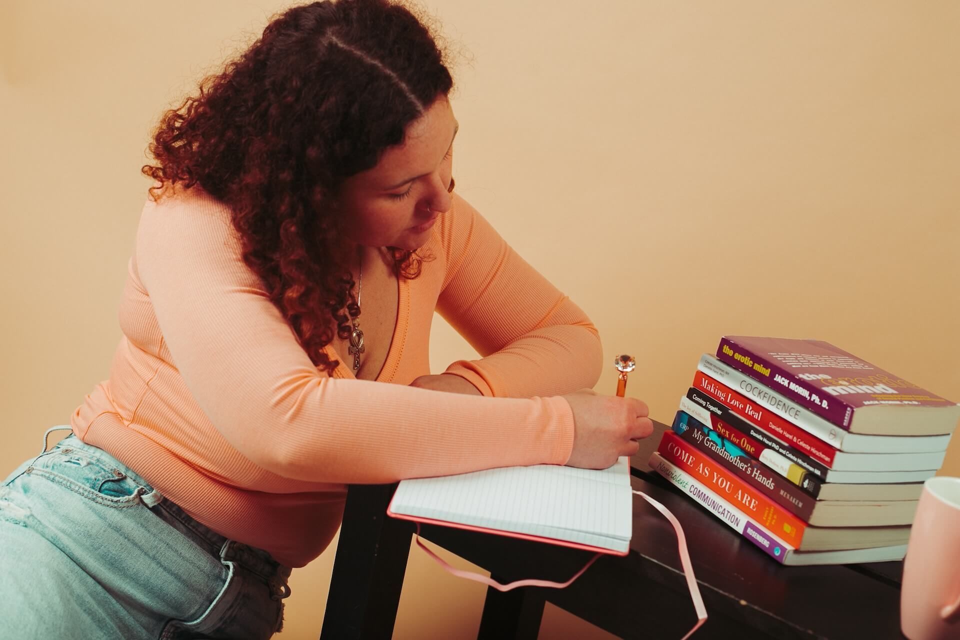 A woman is sitting at a table writing in a notebook.