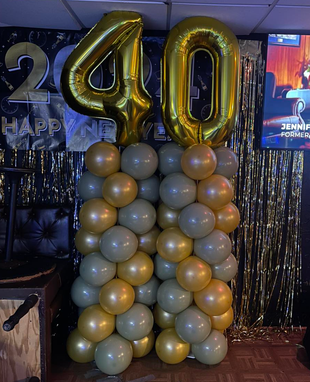 Gold “40” balloons above a gold-gray balloon column at a decorated birthday celebration.