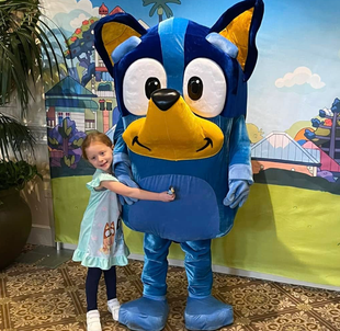 Child hugging a large Bluey mascot at a birthday party.
