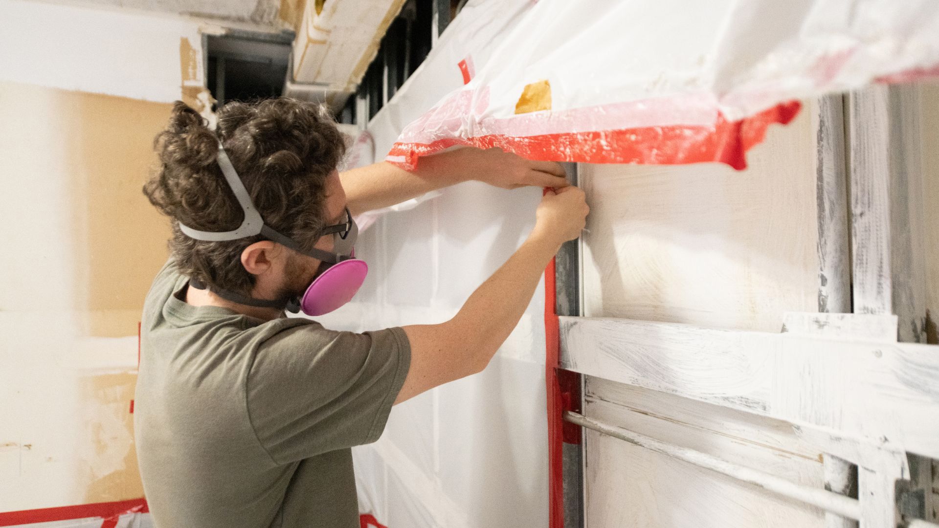 a man wearing a mask and goggles is working on a wall .