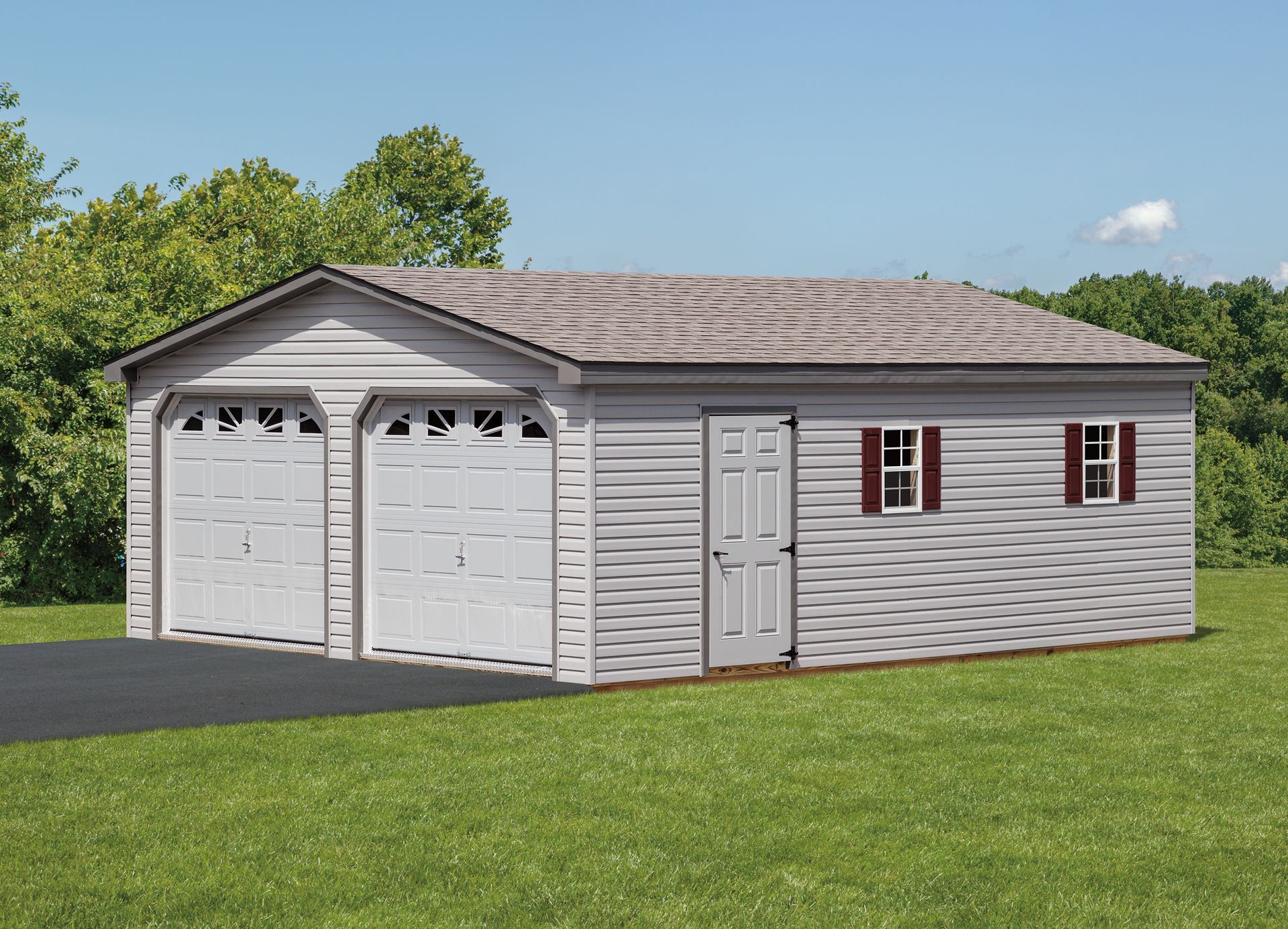 Gray two-car garage with a brown roof and a side door, set on a green lawn with trees.