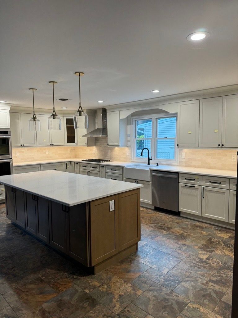 Modern kitchen with large island, white cabinets, stainless appliances, and a window over the sink.