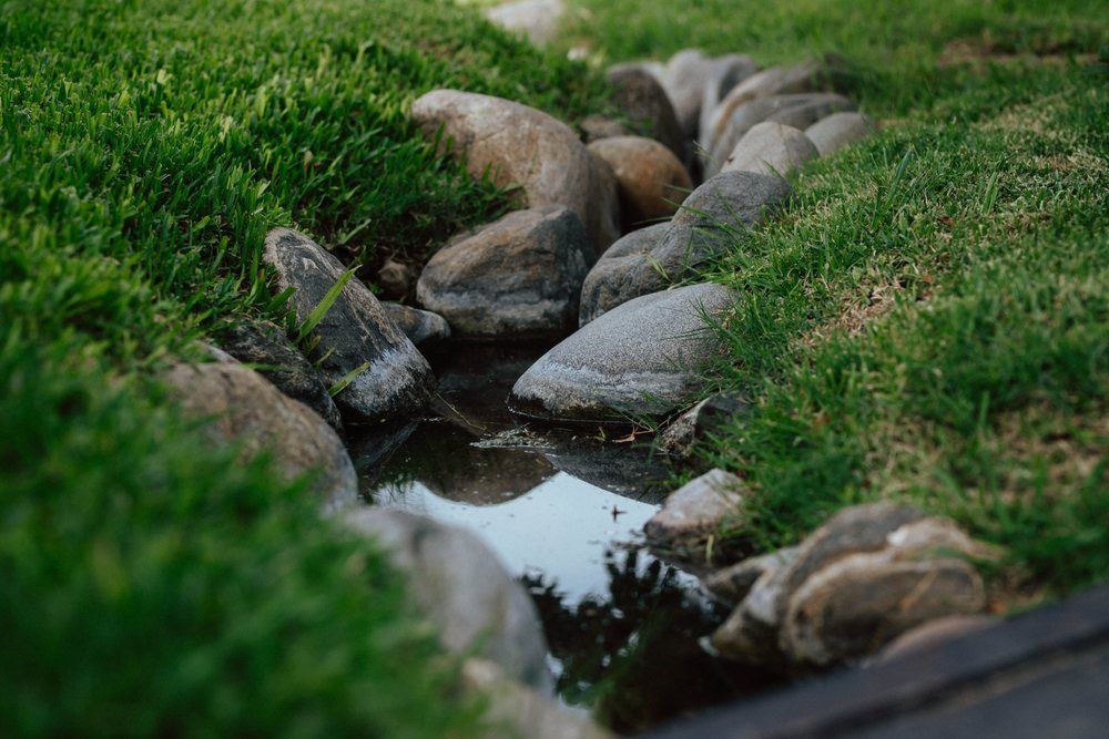 Rock-lined channel carrying runoff through grass
