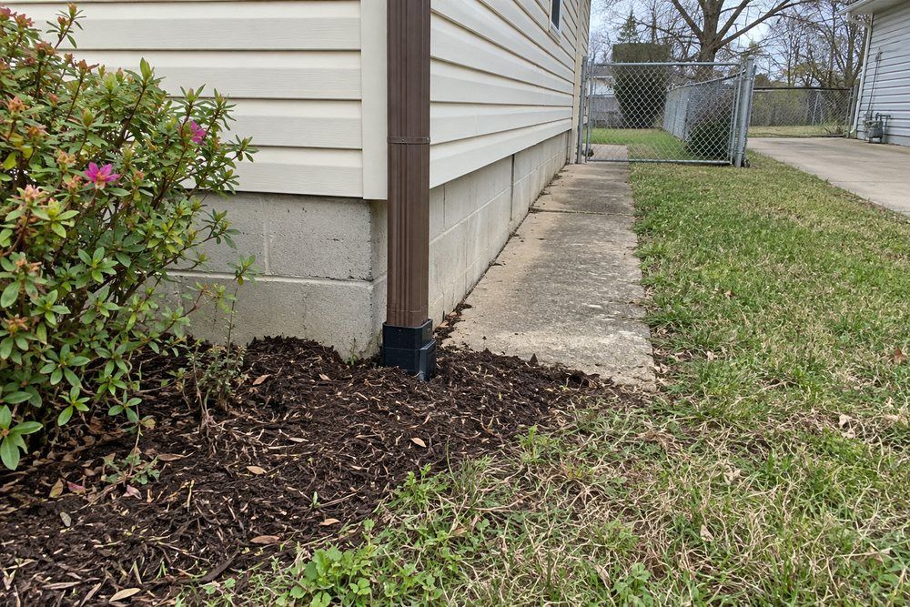 Buried downspout connection beside an older Jonesboro-area home