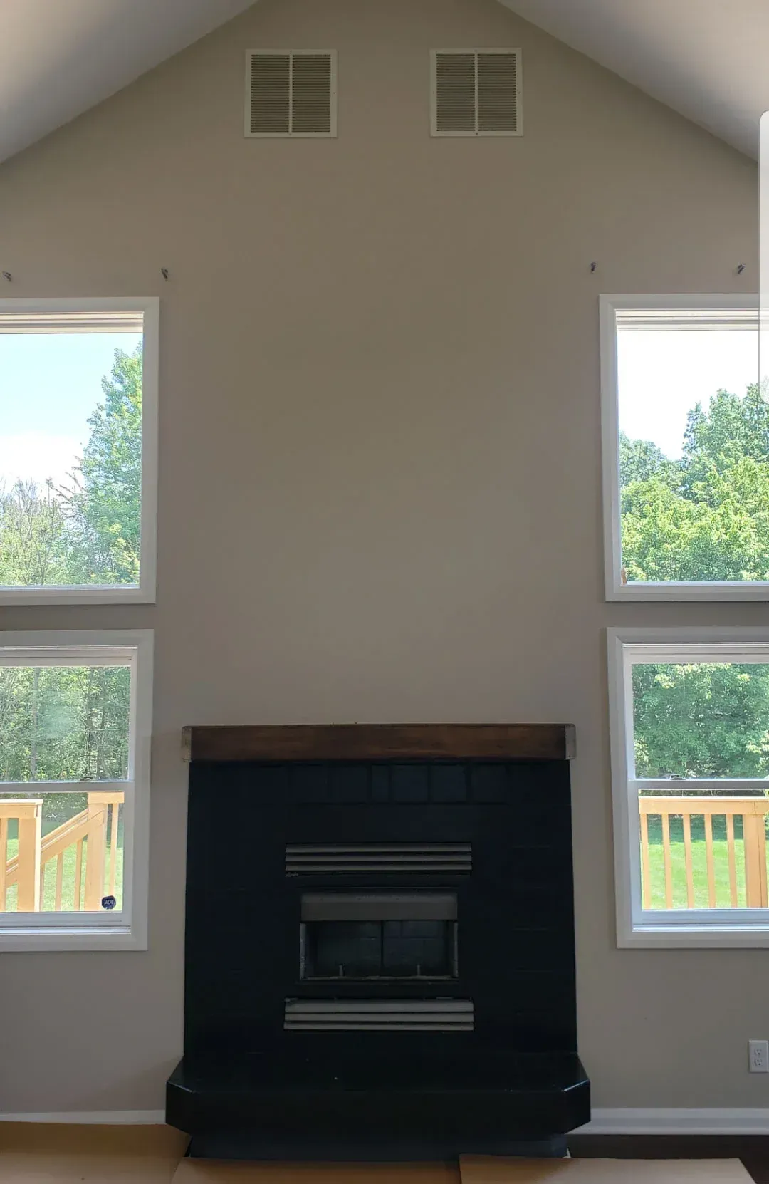Bright living room with vaulted ceiling, black fireplace, and tall windows on both sides.