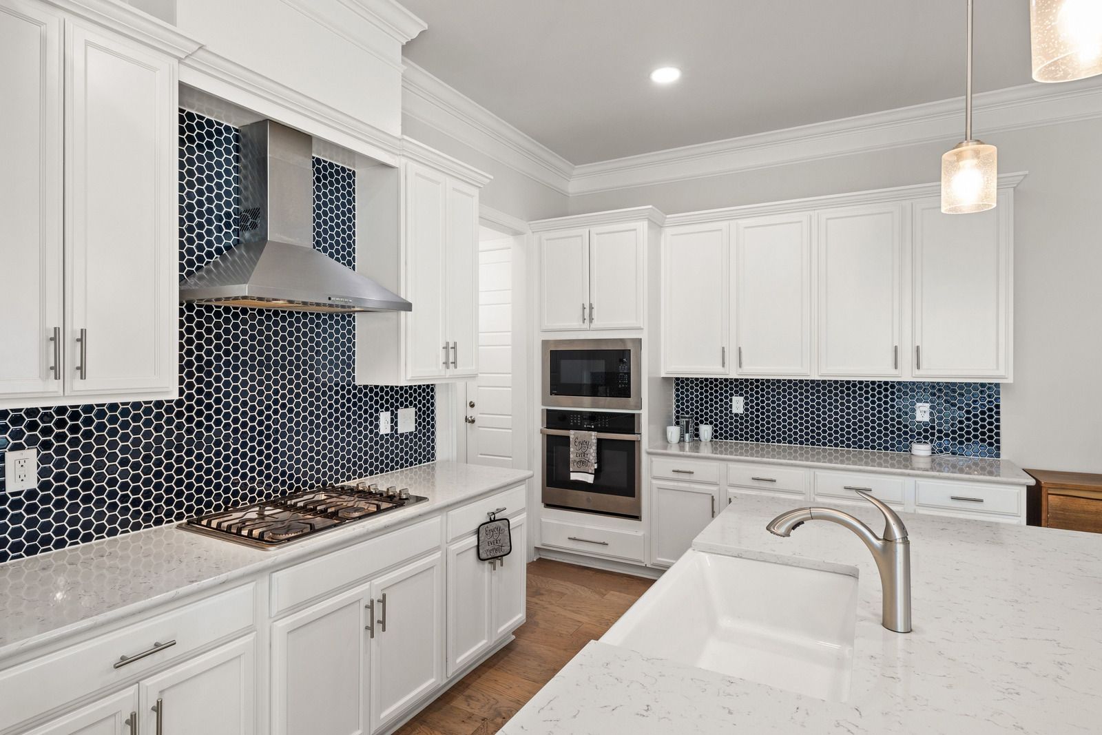 Bright white kitchen with blue mosaic backsplash, stainless appliances, and marble island