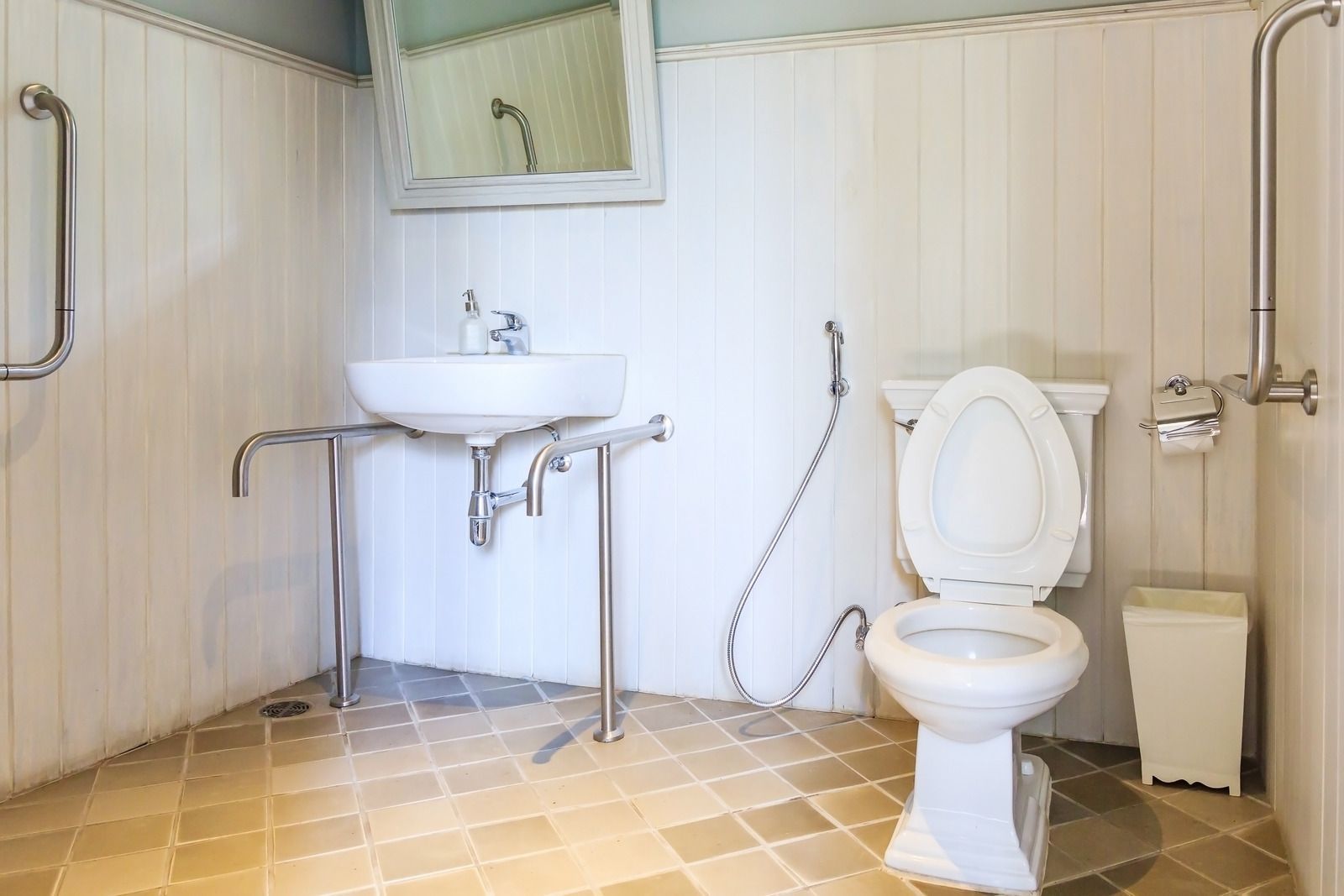 Accessible bathroom with sink, toilet, grab bars, and tiled floor