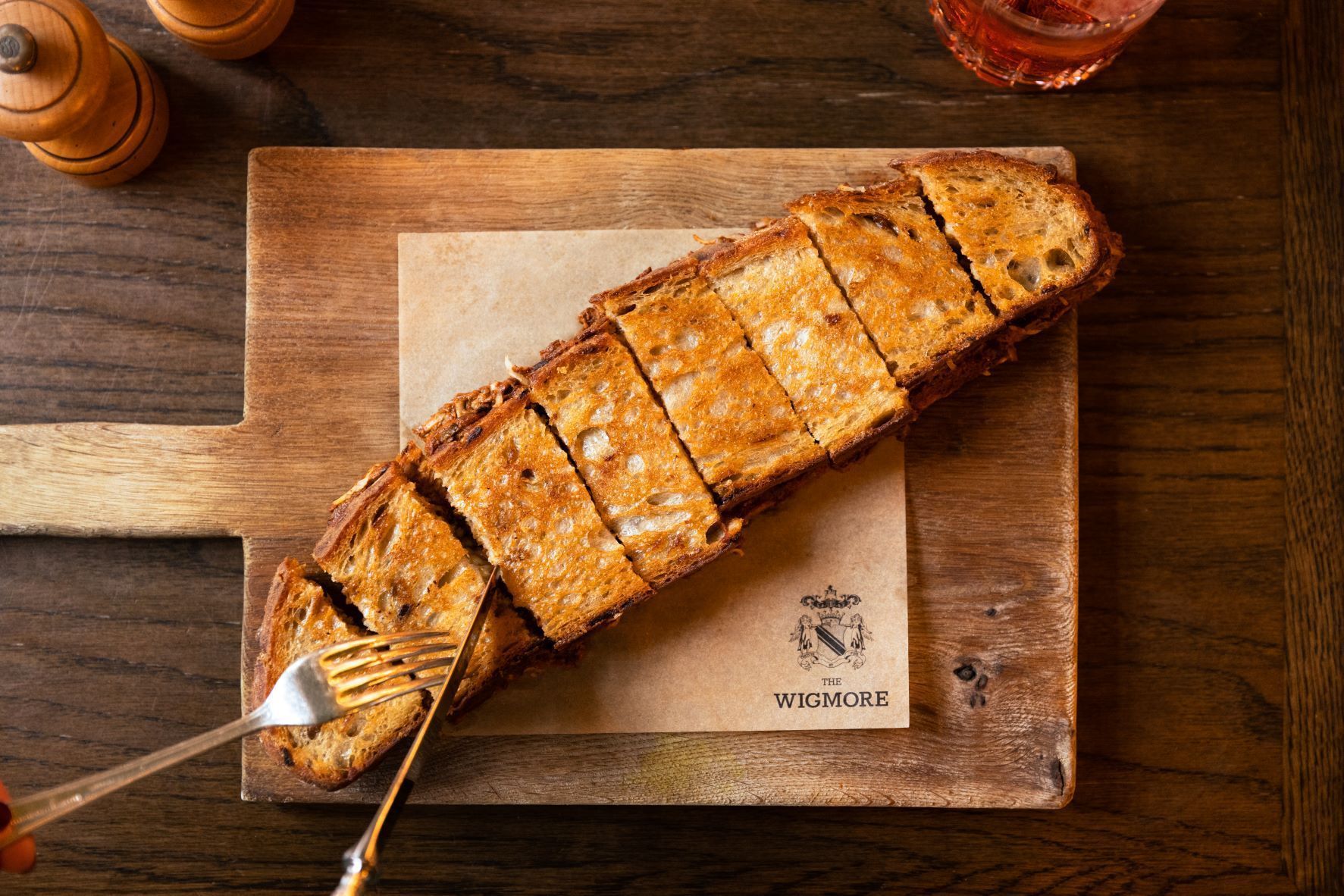 Grilled whole fish on a wooden cutting board with lemon slices on a rustic table