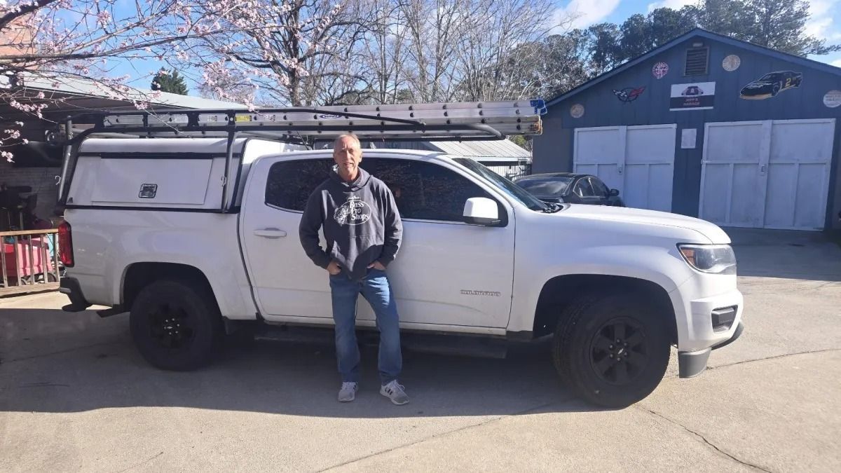 A man is standing next to a white truck in a parking lot.