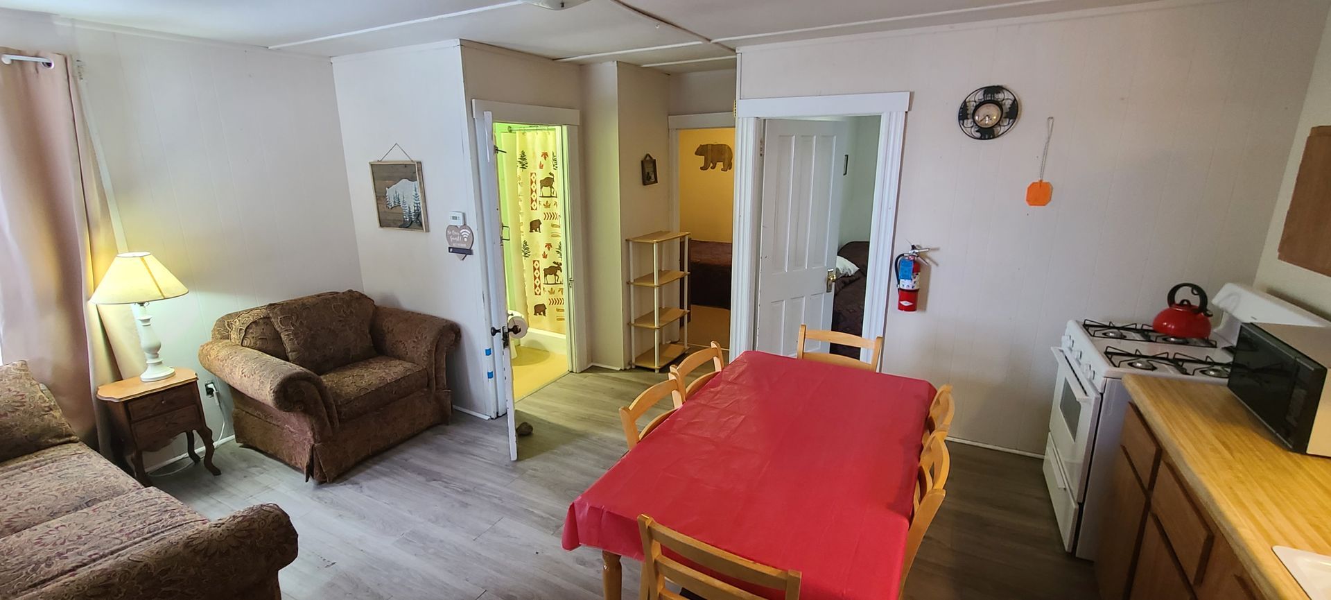 A living room with a couch , chair , table and kitchen.