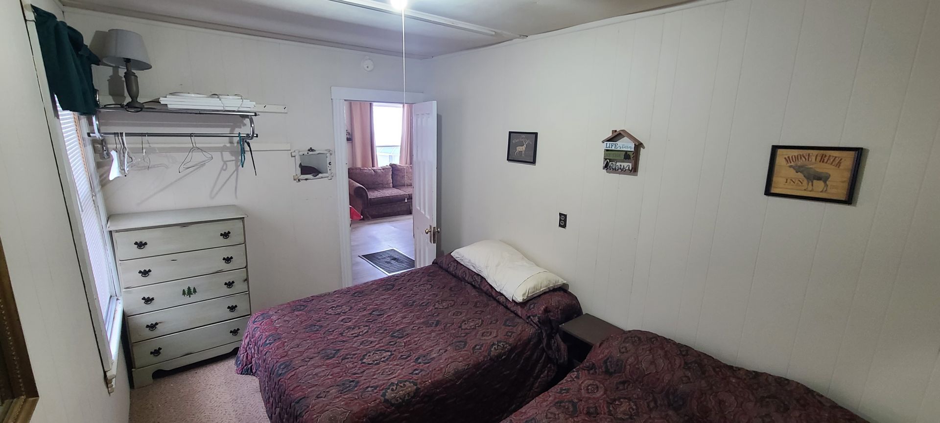 A bedroom with two beds and a dresser.