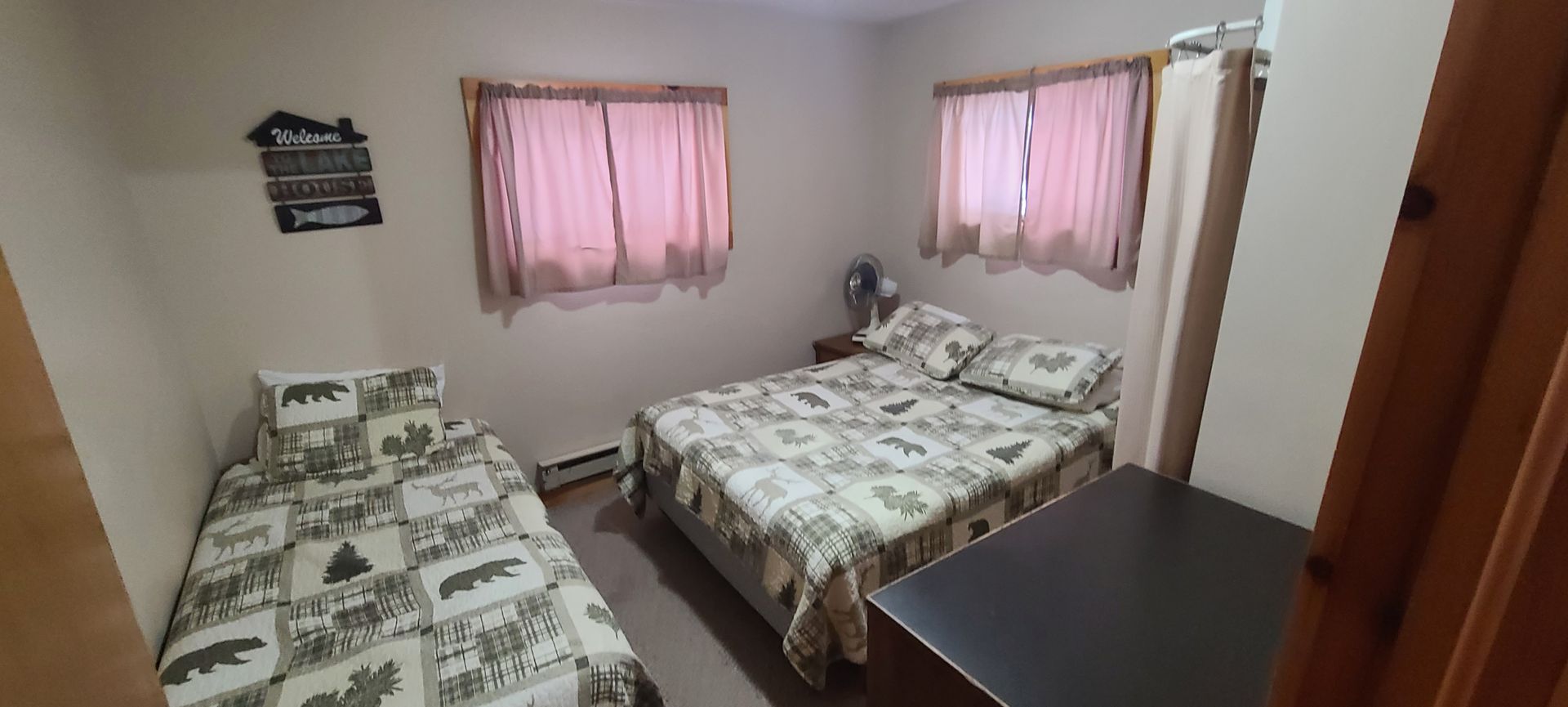 A bedroom with two beds and two windows.