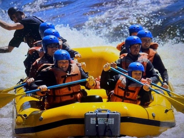 A group of people are rafting down a river in a yellow raft