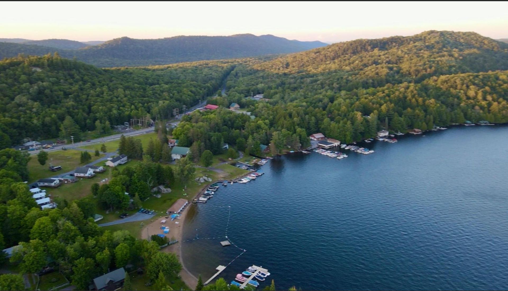 An aerial view of a lake surrounded by trees and mountains.