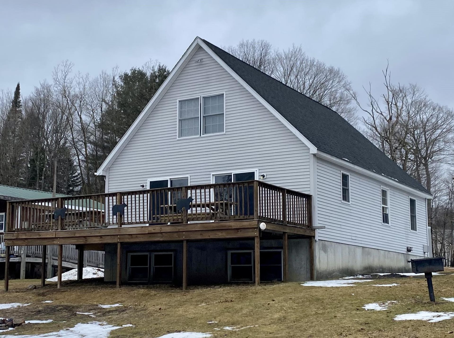 A white house with a black roof and a large deck