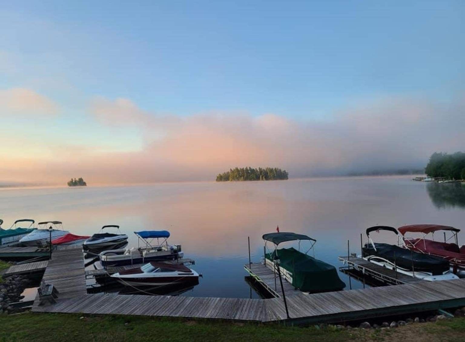 A group of boats are docked at a dock on a lake.