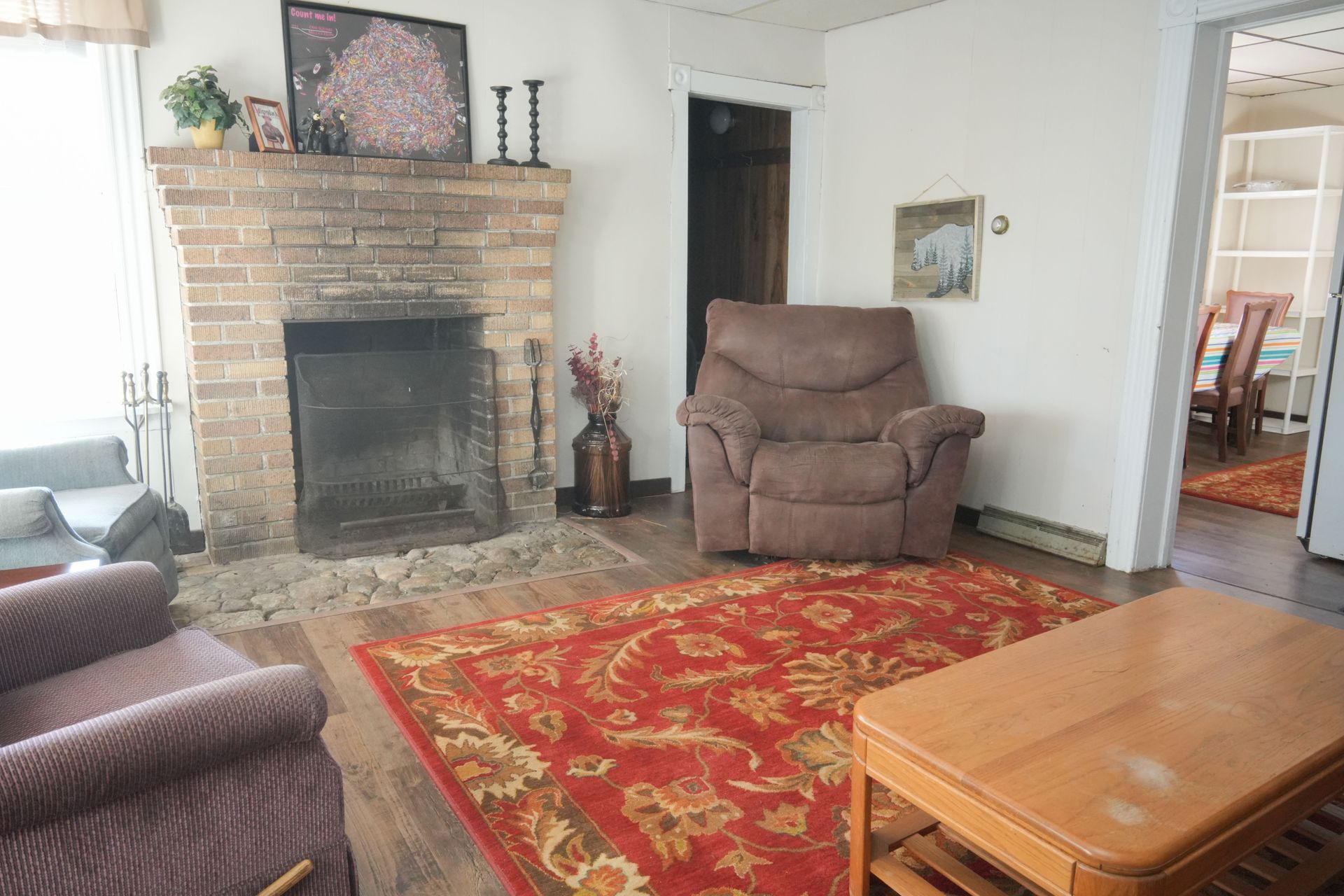 A living room with a fireplace , chair , table and rug.