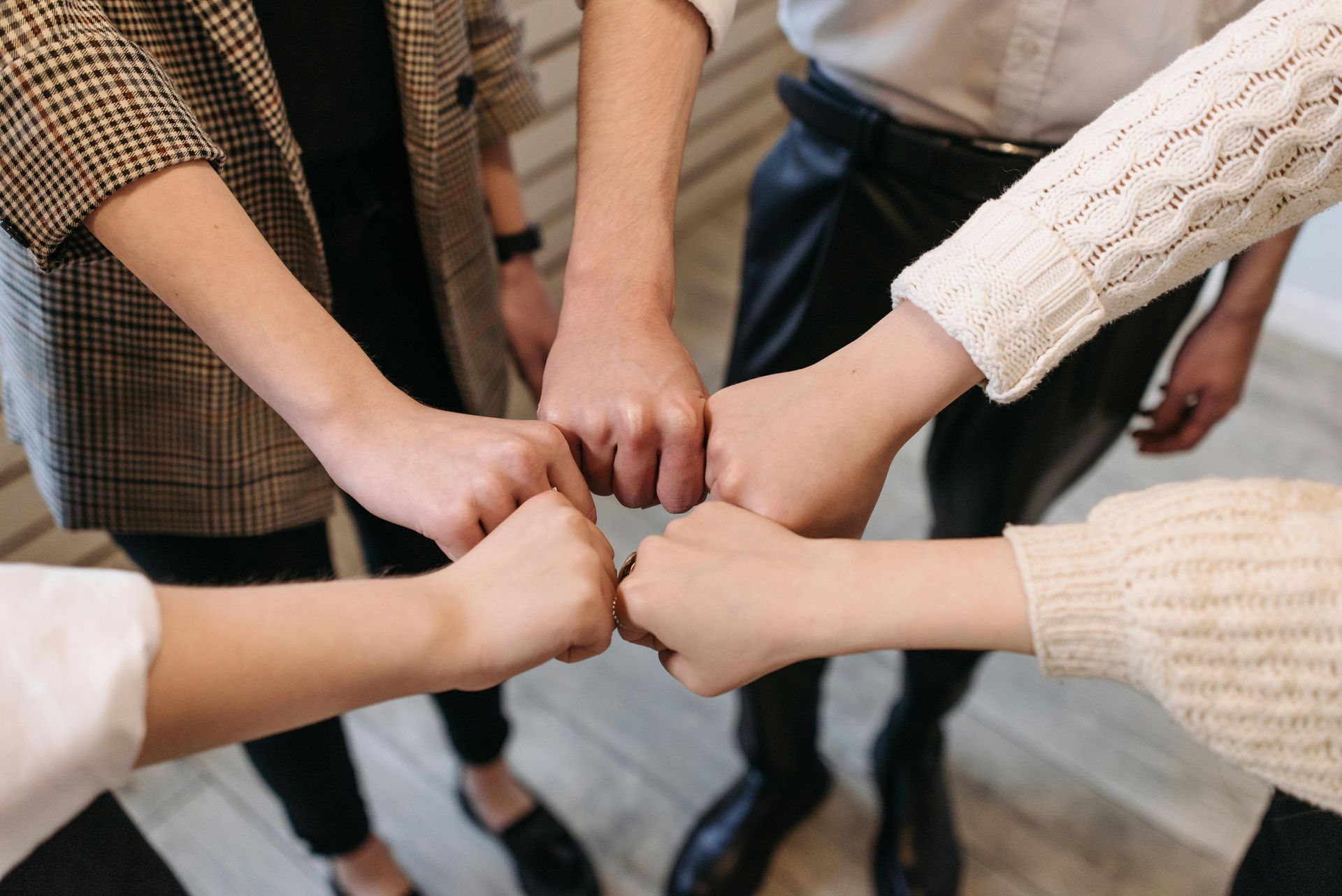 Five people with fists bumped together, demonstrating teamwork and unity.